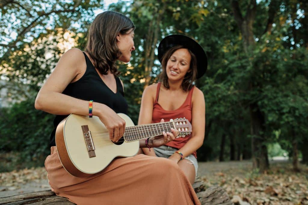 mujer embarazada su pareja tocando ukelele parque mientras disfrutan compania demas